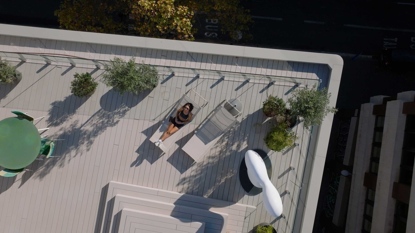 Aerial drone shot of a woman relaxing on a rooftop terrace